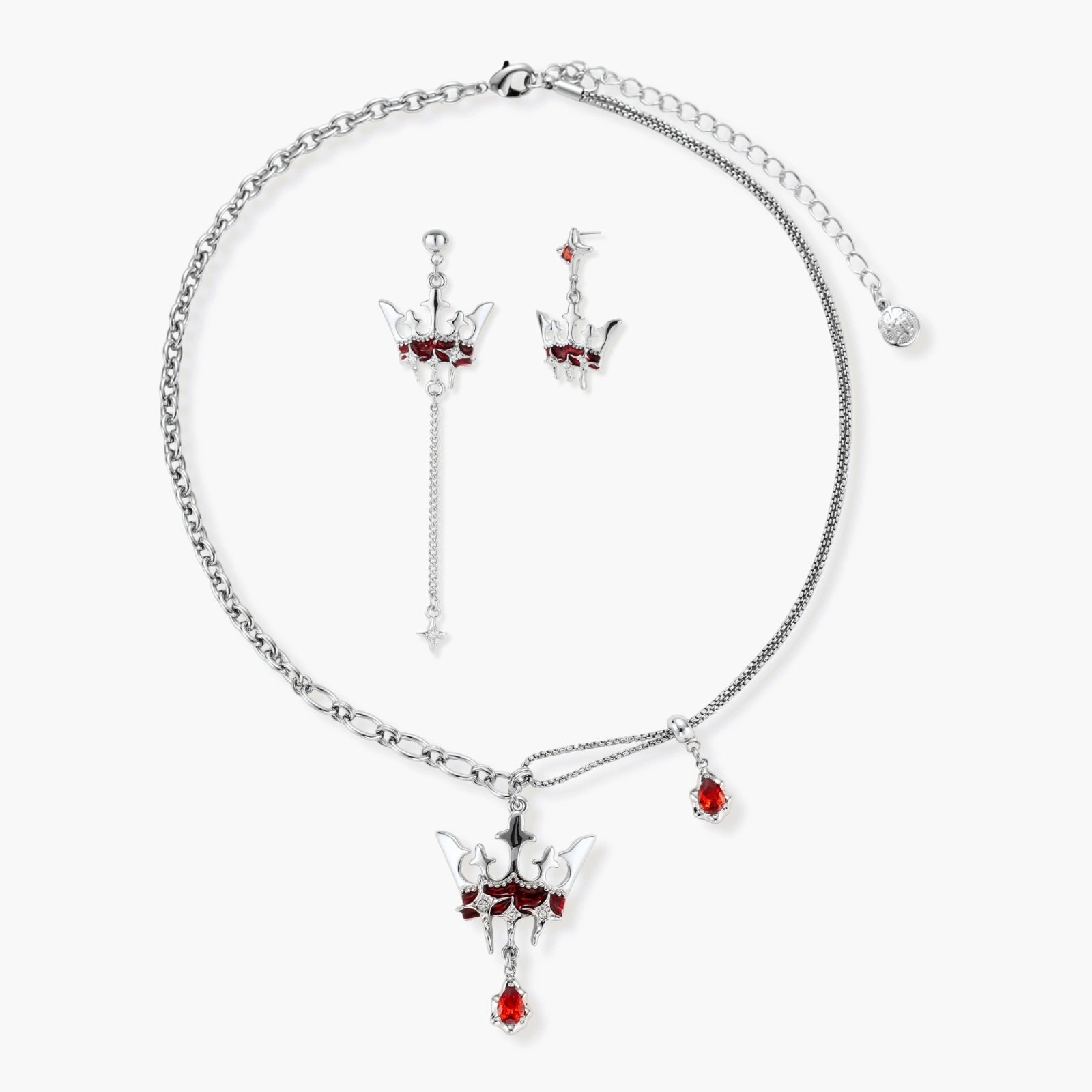 Silver-tone crown pendant with red zirconia stones and matching asymmetrical earrings on cream background