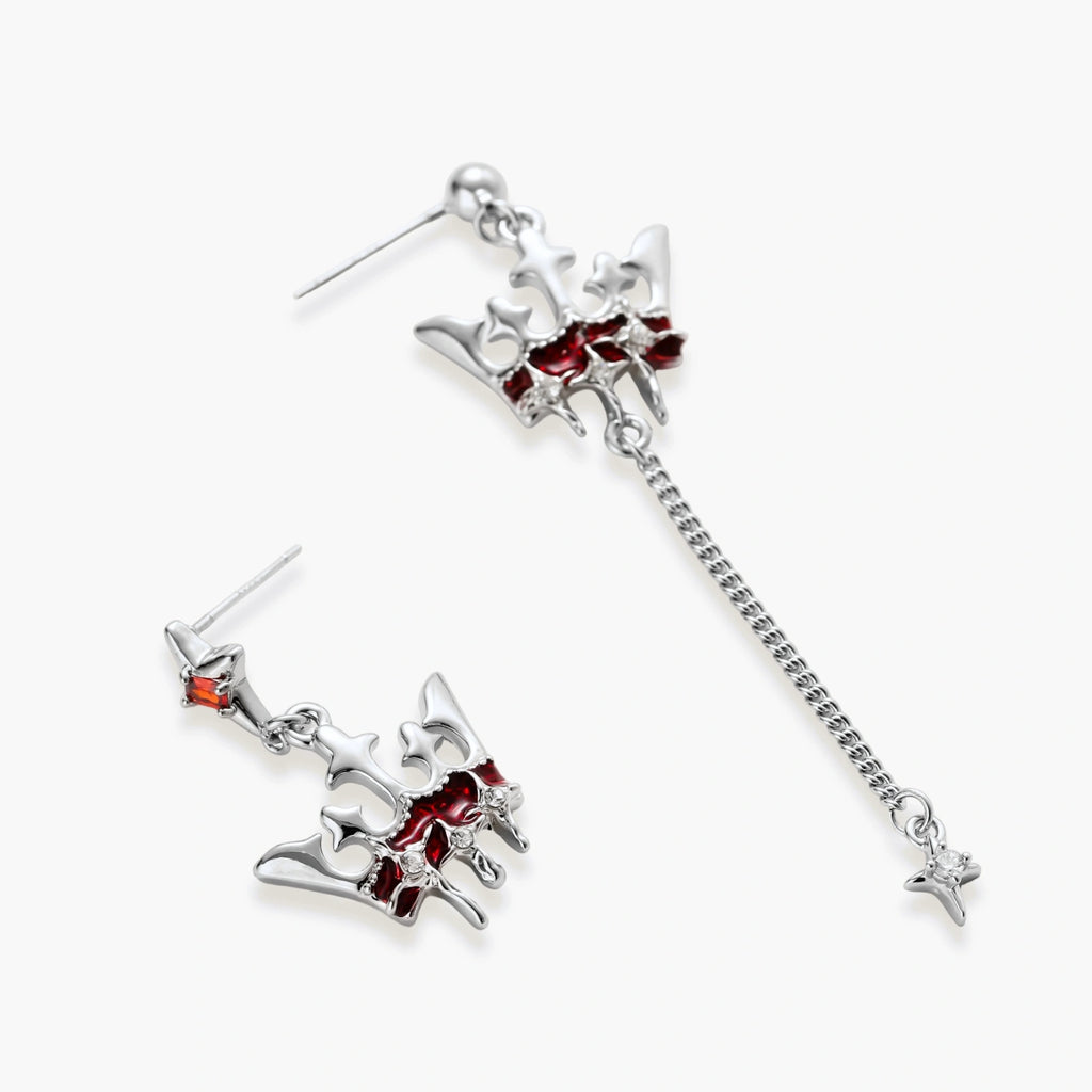 Silver-tone crown pendant with red zirconia stones and matching asymmetrical earrings on cream background