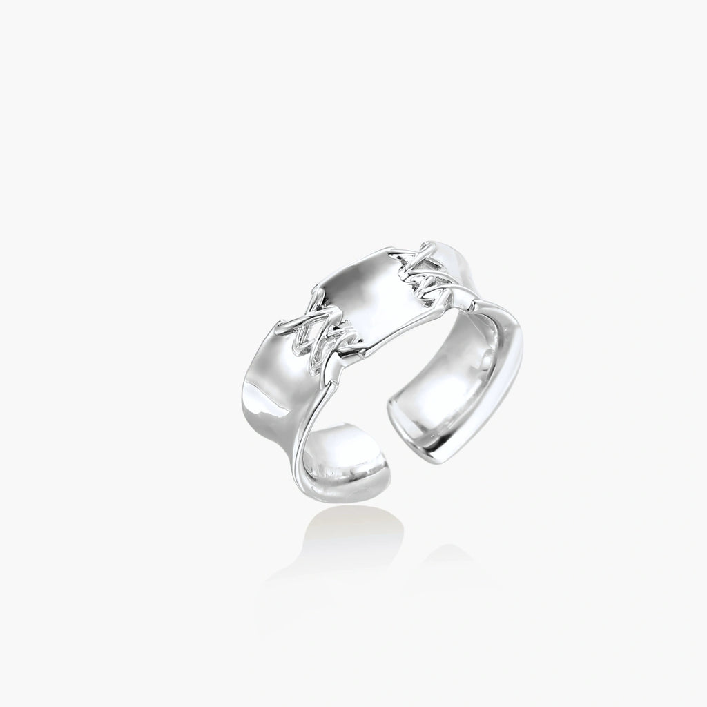 Adjustable silver-toned ring with sculptural stitch design across polished white gold-plated brass band
