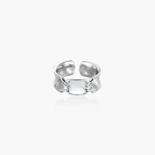 Adjustable silver-toned ring with sculptural stitch design across polished white gold-plated brass band