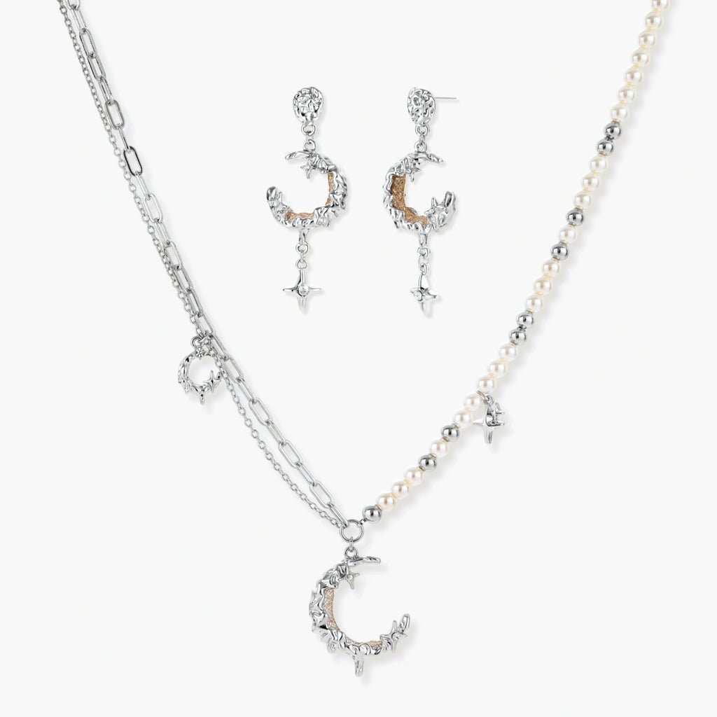 Mixed-metal jewelry set featuring layered necklaces with crescent moon pendant and pearl beads, plus matching star-drop earrings.