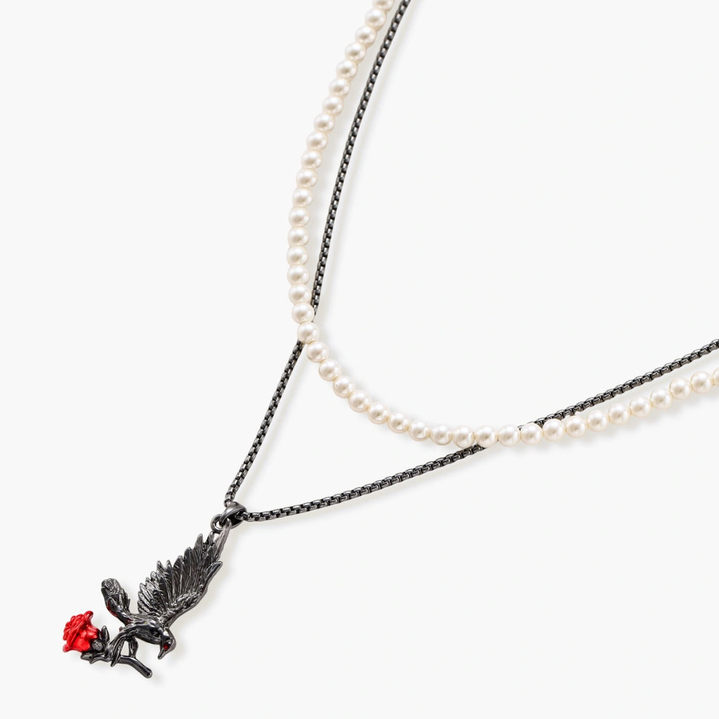 Dark gunmetal jewelry set featuring detailed raven pendants carrying red enamel roses with layered pearl and chain necklaces