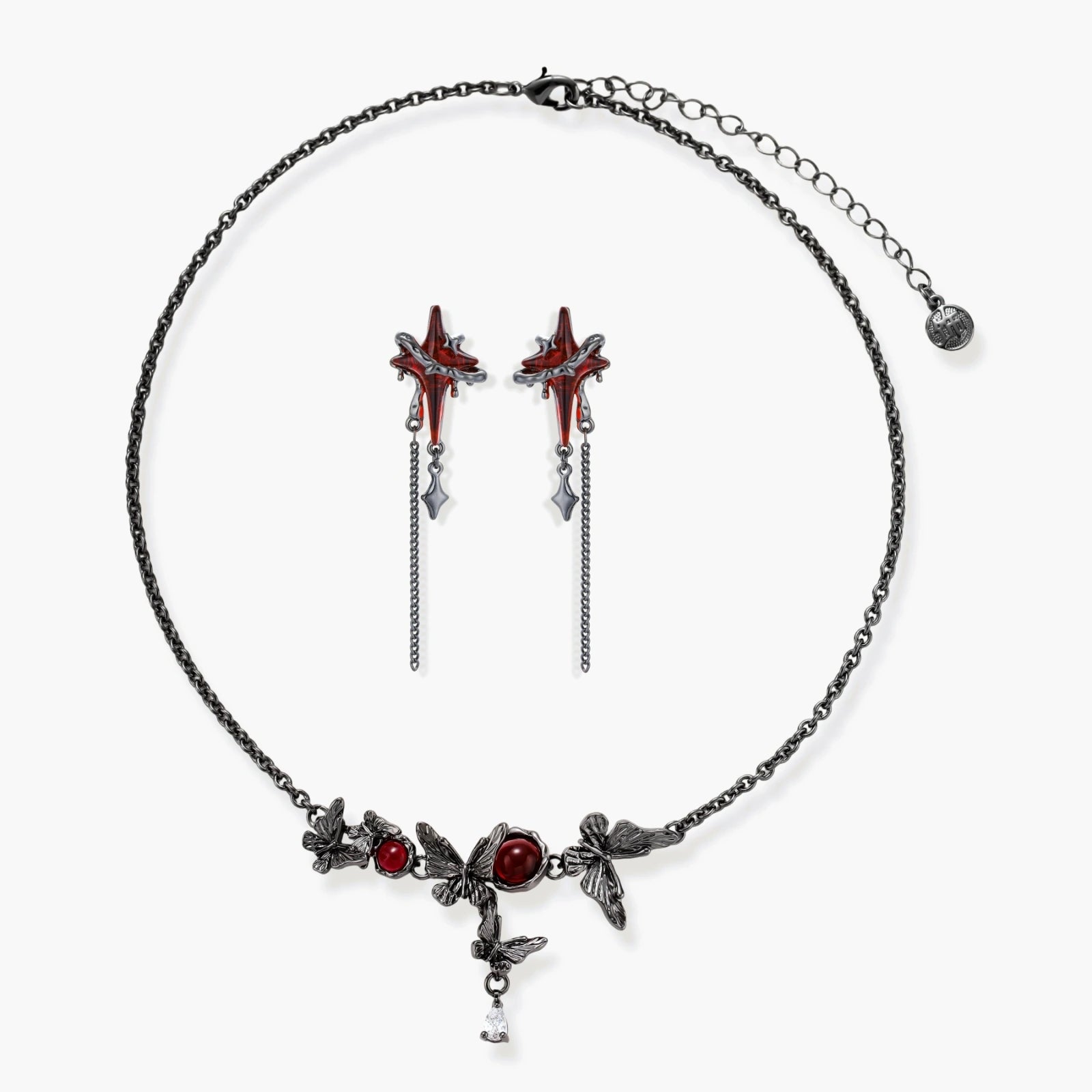Gothic jewelry set with red resin cross pendants wrapped in dark metal chains on cream background.